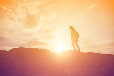 Silhouette woman standing on mountain against sky during sunset