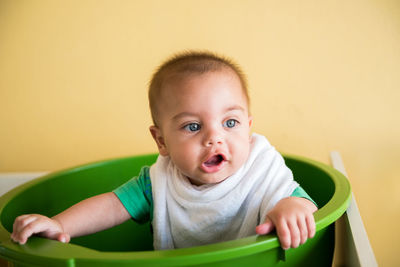 Close-up cute baby boy sitting in bucket at home