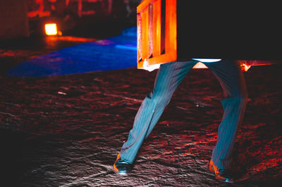 Low section of man carrying wood while standing on street at night