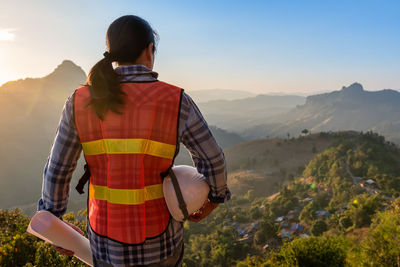 Rear view of man standing on mountain against sky