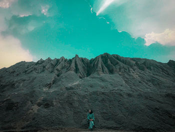 Rear view of person standing on rock against sky