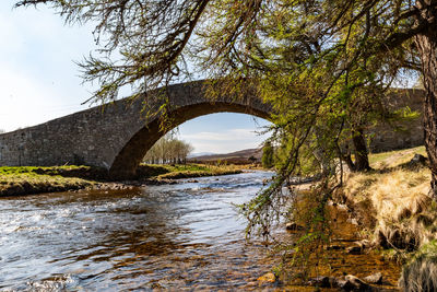 Arch bridge over river against sky