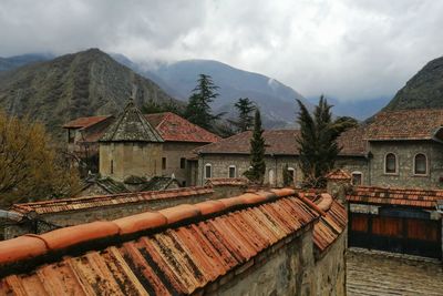 An ancient christian monastery in a mountain gorge against the backdrop of a cloudy sky.