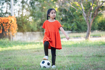 Full length of smiling boy playing soccer on field