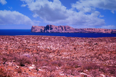 Scenic view of rocks by sea against sky