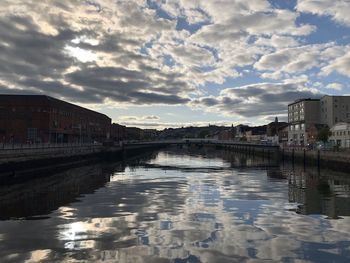 Bridge over river amidst buildings in city against sky