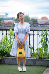 Full length of a smiling young woman standing outdoors