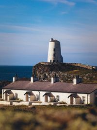 Lighthouse amidst sea and buildings against sky