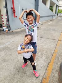Full length portrait of siblings standing on footpath