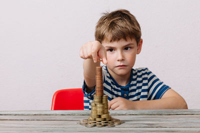 Boy stacking coins on wooden table