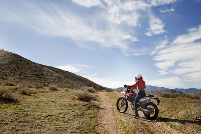 Side view of female biker sitting on motorcycle at countryside