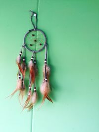 Low angle view of dreamcatcher hanging on green wall