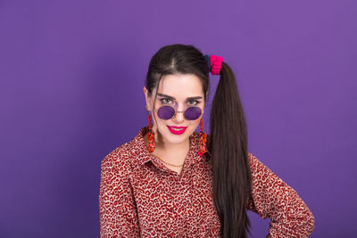 Portrait of young woman standing against blue background