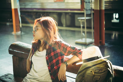 Young woman sitting on bench at railroad station platform