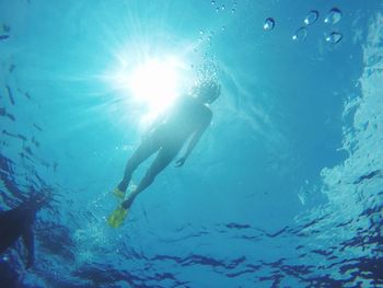 Low angle view of man swimming undersea during sunny day