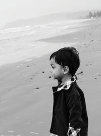 Side view of boy standing on sand at beach