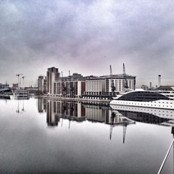 Buildings by river against sky in city