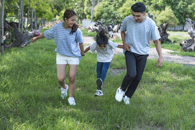 Rear view of friends walking on grassy field