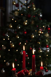 Illuminated candles against christmas tree