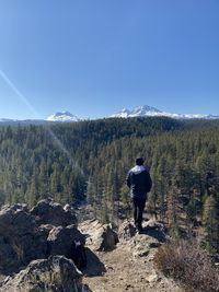 Rear view of man standing on mountain against sky