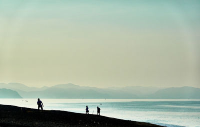 Silhouette people on beach against sky