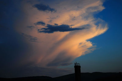 Low angle view of silhouette built structure against cloudy sky