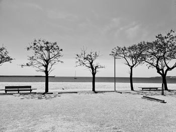 Empty bench by sea against sky