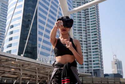 Low angle view of woman using virtual reality simulator in city