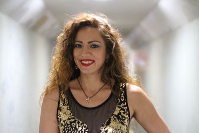 Portrait of young woman standing against wall