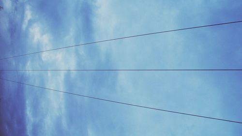 Low angle view of power lines against blue sky