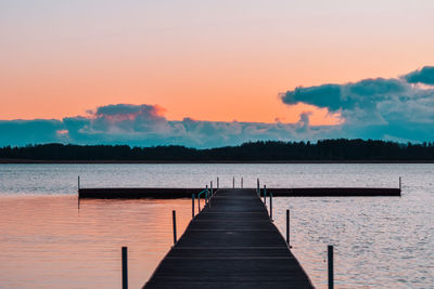 Pier over lake against sky during sunset