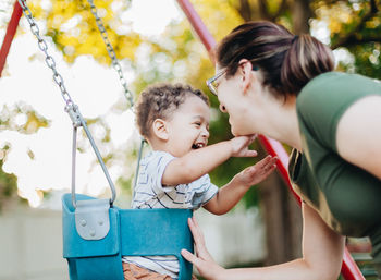 Side view of woman holding swing at playground