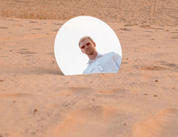 Rear view of man with umbrella on sand at sandy beach