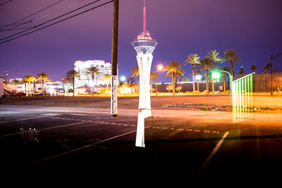 Illuminated light trails on city street against clear sky at night