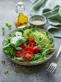 Fresh summer salad with arugula, red cherry tomatoes, basil, eggs and avocado. vegan food. 