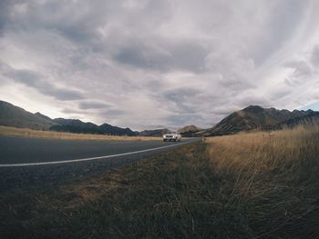 Scenic view of road amidst field against sky