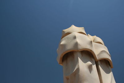 Low angle view of statue against building against clear blue sky