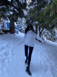 Full length rear view of woman walking on snow covered field