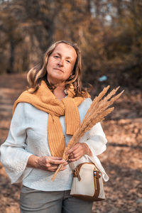 Portrait of a smiling young woman holding autumn leaf