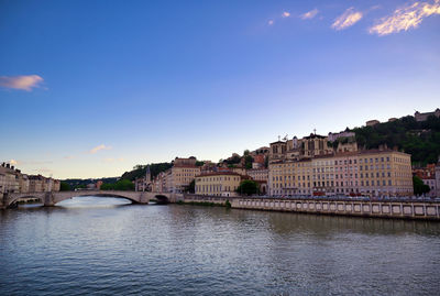 Arch bridge over river against buildings in city