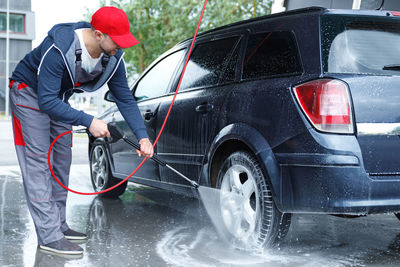 Side view of man cleaning car