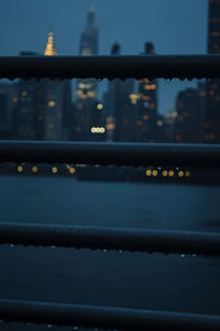 Close-up of illuminated railing by building in city