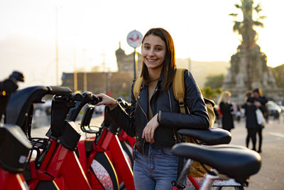 Woman smiling next to a red rental bikes.