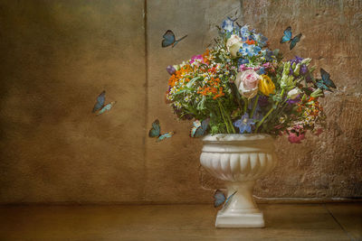 Close-up of flower vase on table against wall