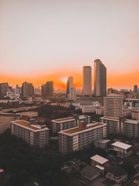 Modern buildings in city against sky during sunset