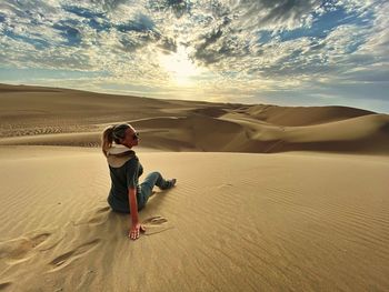 Full length of man on sand dune in desert against sky