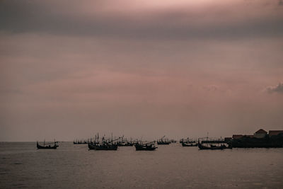 Sailboats sailing in sea against sky during sunset