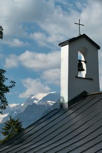 Low angle view of cross on roof of building against sky