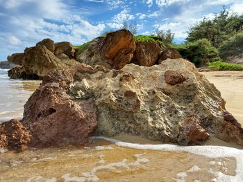 Rock formation on beach against sky