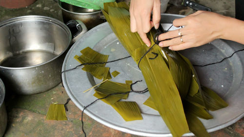 Cropped hands packing food in leaves on tray 